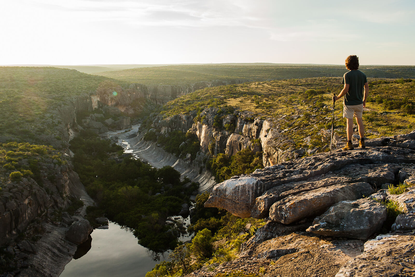 A hiker overlooking a canyon at golden hour in the Texas Hill Country