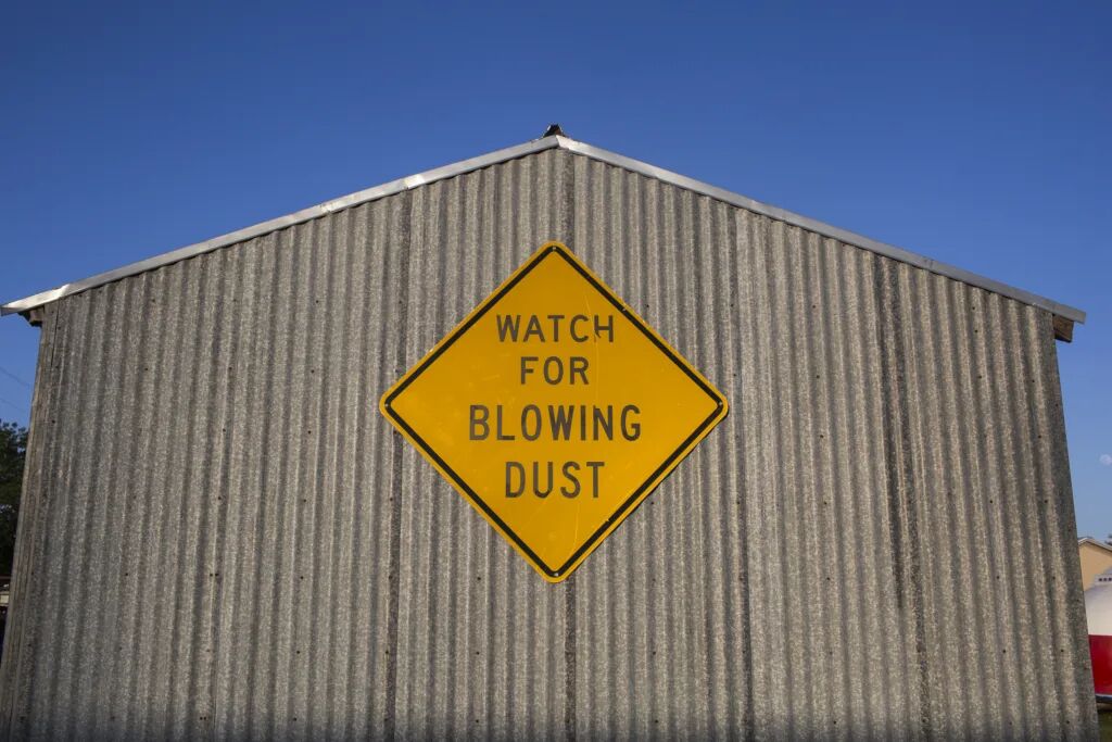 A weathered barn and a blowing-dust warning in the Panhandle